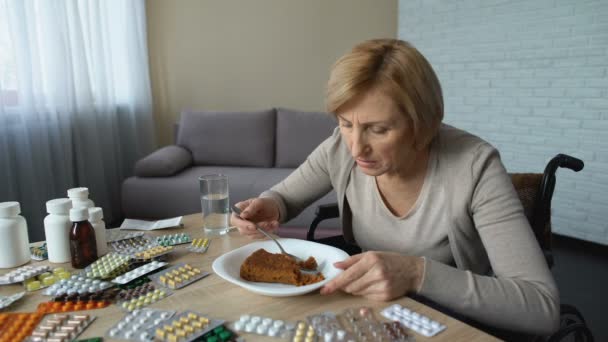Zieke gehandicapte vrouw proberen te eten dessert aan tafel met pillen, revalidatie — Stockvideo
