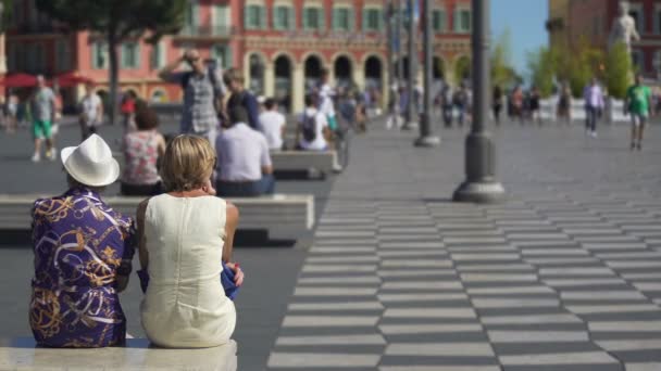 NICE, FRANCIA - CIRCA JUNIO 2016: Turistas en la ciudad. Dos mujeres descansando en el banco, la vida activa en el centro de la ciudad, día de verano soleado — Vídeo de stock