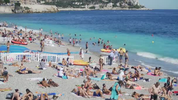 NICE, FRANCIA - CIRCA JUNIO 2016: Gente en la playa. Playa pública abarrotada en la orilla del mar, muchas personas tomando el sol o salpicando en el agua — Vídeos de Stock