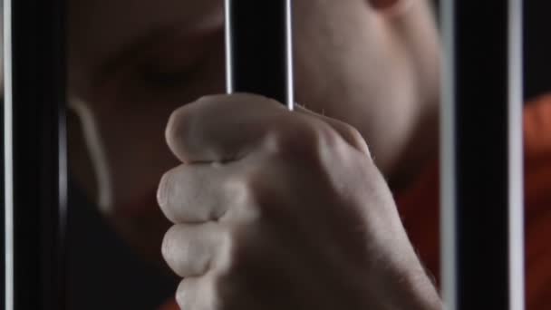 Сердито выглядящий арестованный мужчина в наручниках с тюремными решетками, наказание — стоковое видео