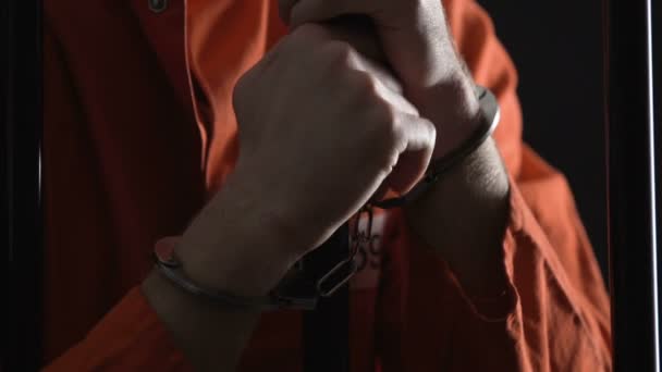 Bilek cep barlar, kötü hapishane koşulları arkasında sürtünme kelepçeli üzgün mahkum — Stok video