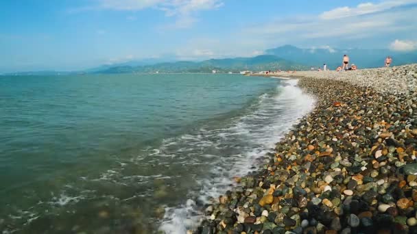 Батуми, Грузия - CIRCA MAY 2017: Люди на пляже. Теплые черноморские волны, плескающиеся на галечный пляж, люди, отдыхающие на берегу — стоковое видео