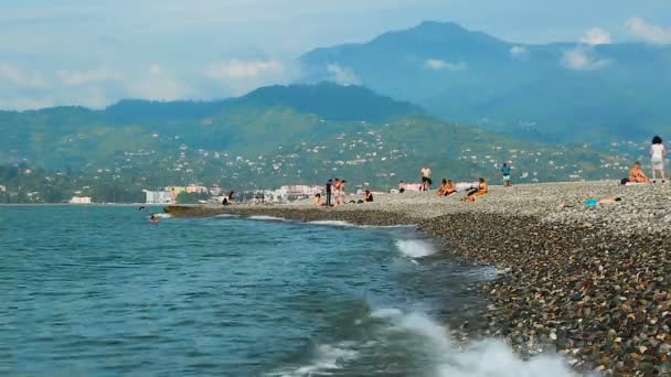 Батумі, Грузія - Circa травня 2017: Люди на пляжі. Туристи, які користуються відпустку на гальковому пляжі, морські хвилі хлюпалися проти берега — стокове відео