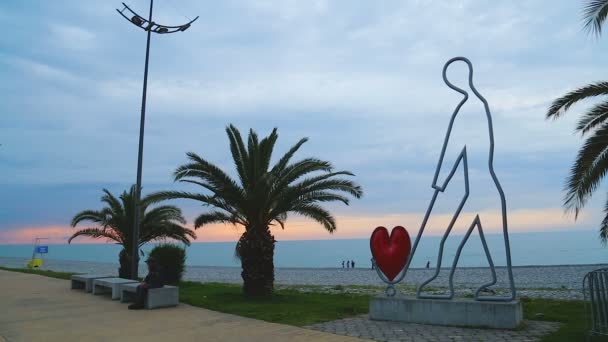 Творческая статуя человека с сердцем в Батуми, друзья-подростки, отдыхающие на море — стоковое видео