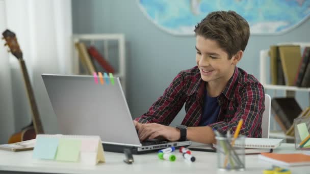 Menino adolescente conversando ativamente com amigos em redes sociais sentados em seu quarto — Vídeo de Stock