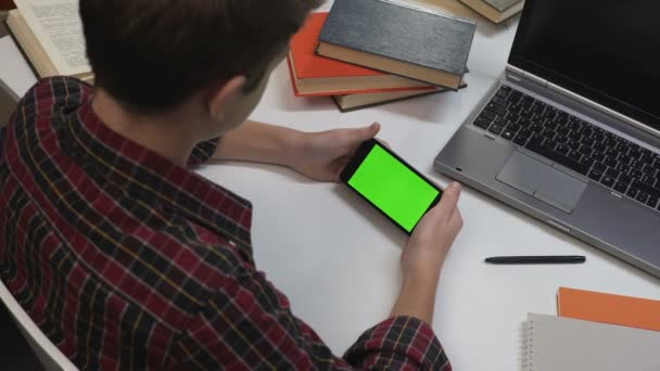 Menino masculino segurando smartphone com tela verde, lendo post on-line, visão traseira — Vídeo de Stock