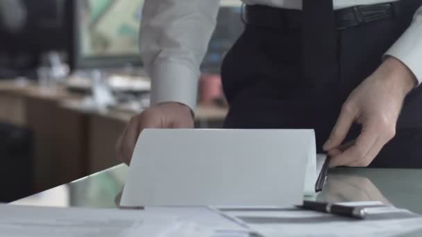 Baas kijken door contract met koffiekopje terwijl secretaris te typen achter — Stockvideo