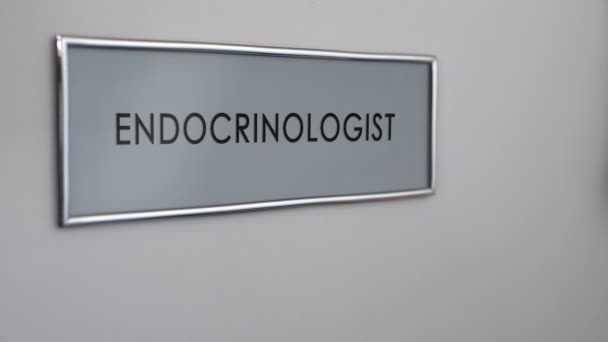 Puerta del consultorio del endocrinólogo, primer plano de la mano del paciente, enfermedad tiroidea — Vídeos de Stock