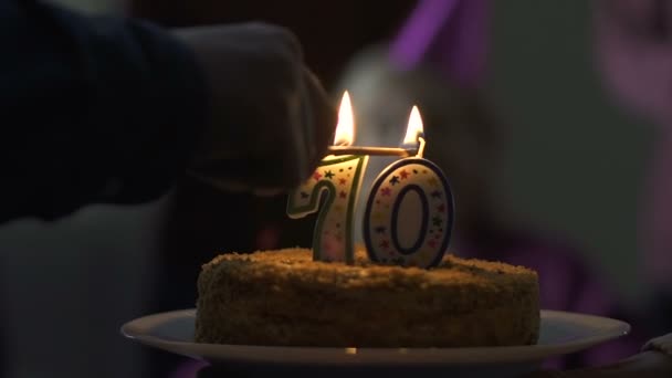 Feliz 70 años de edad, mujer soplando velas en pastel de cumpleaños en la fiesta en casa — Vídeo de stock