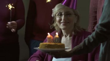 Üst düzey kadın dışarı üfleme kutluyor 80 doğum günü kek ve gülümseyen, mumlar