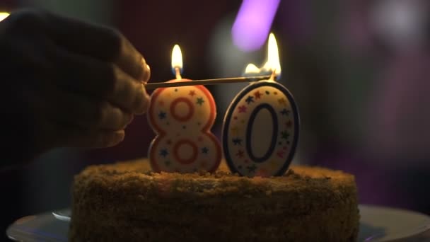 Mão acender velas bolo de aniversário, celebração de 80 anos, sobremesa saborosa — Vídeo de Stock