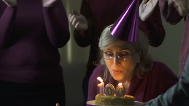 Old woman blowing out cake candles on 100 birthday party, volunteers support — Stock Video