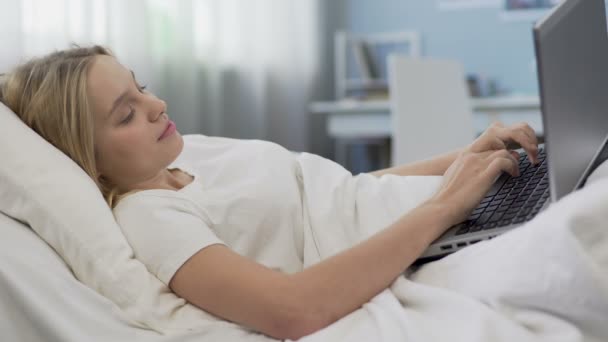 Teenage girl lying in bed with laptop, social networking addiction problem — Stock Video