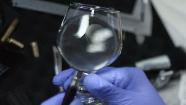 Private detective viewing victim fingerprints on wine glass at crime scene — Stock Video