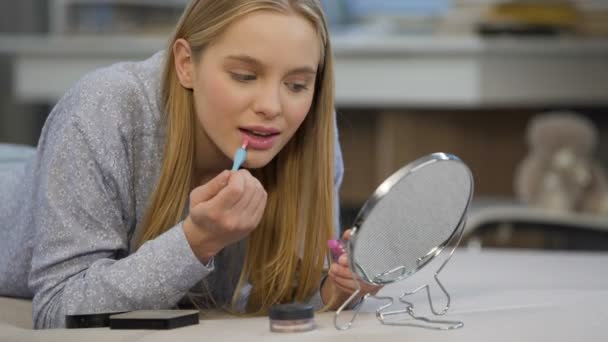 Kaukasische Studentin versucht, Glanz-Lippenstift in der Nähe von Spiegel, Gesicht verschönern — Stockvideo