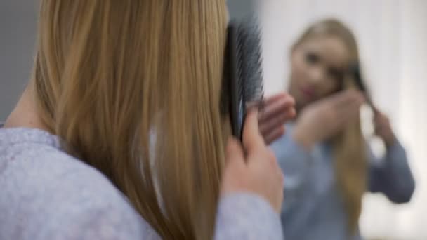 Dospívající žena česání vlasy hladké poblíž zrcadlo místnost, hydratační šampon — Stock video
