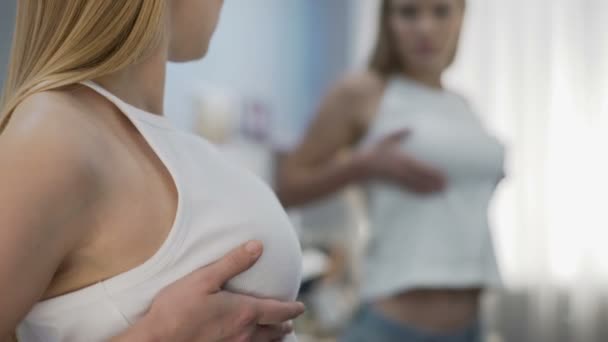 junge Frau überprüft Brust im Spiegel, Krebs-Selbstuntersuchung, Gesundheitsgefahr