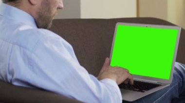 Kanepede oturan ve dizüstü bilgisayar, serbest çalışma yeni makale yazarak yetişkin blogger