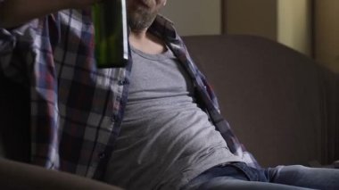İşsiz adam kanepede oturan ve şişelenmiş bira, depresyon içiyor onun 30s