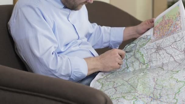 Homme regardant la carte à travers loupe et la planification de son voyage d'été, Voyage — Video