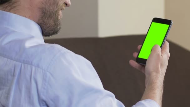 스마트폰 애플리케이션과 웃는, 녹색 화면을 스크롤 하는 수염과 성인 남자 — 비디오