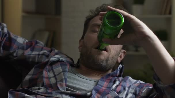 Guy drinken bier uit fles en vallen in slaap sofa, alcoholisme en slechte gewoonten — Stockvideo