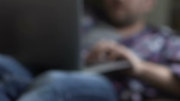 Uvolněné muž ležel na gauči s notebookem a sleduje obsah jen pro dospělé, chatování — Stock video