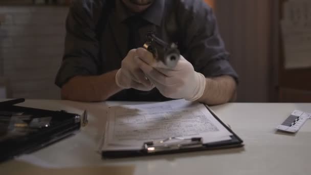 Criminalist examining gun from murder scene, working on case in police station — Stock Video