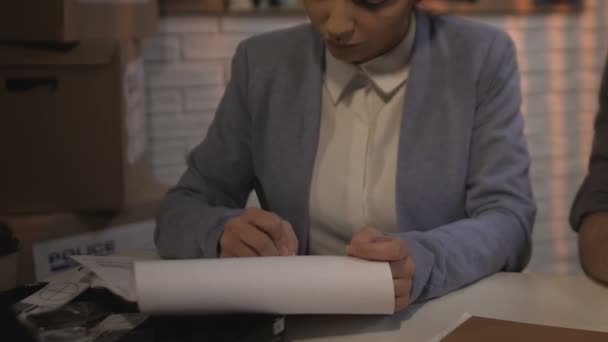 Feminino criminalista preenchimento protocolo enquanto seu colega examinando provas — Vídeo de Stock