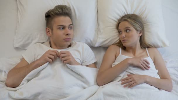 Barátnője az ágyban, és barátja érzi magát szégyelli, szexuális probléma, a pár által vigyorgott — Stock videók