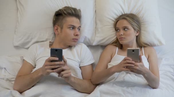 Pareja casada navegando por Internet en teléfonos inteligentes en la cama, falta de comunicación — Vídeo de stock