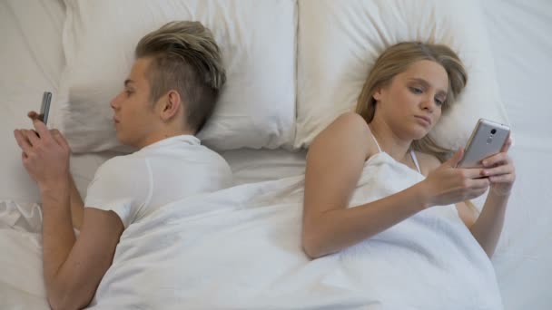 Couple lying back to back in bed with smartphones, social networks, ignore — Stock Video