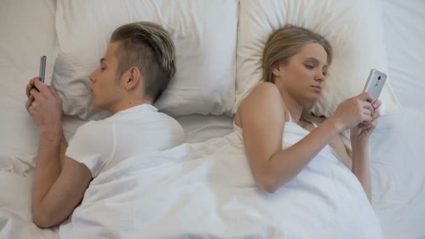 Hombre y mujer poniendo gadgets bajo almohadas, comunicación en las redes sociales — Vídeos de Stock