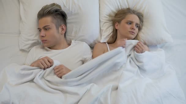 Upset young couple lying in bed, angrily pulling blanket, conflict in relations — Stock Video