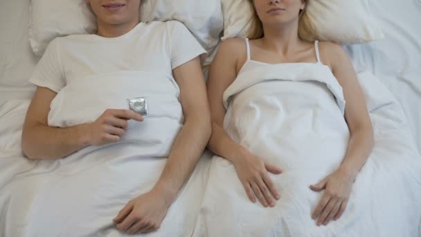 Uomo che tiene preservativo e fidanzata mostrando pollici in su, atteggiamento responsabile — Video Stock