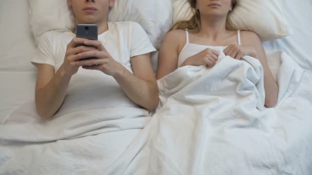 Boyfriend playing smartphone games in bed, ignoring girlfriend, couple problem — Stock Video