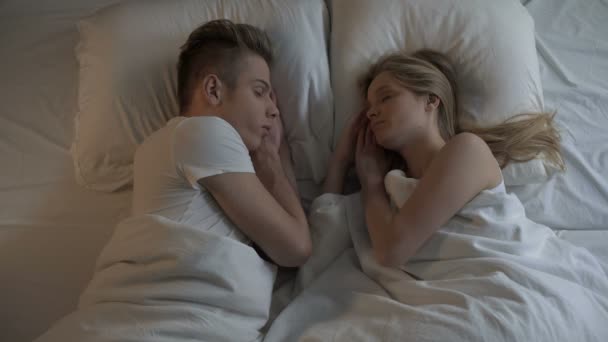 Молодая пара мечтает в постели на удобном матрасе и постельном белье, тихая ночь — стоковое видео