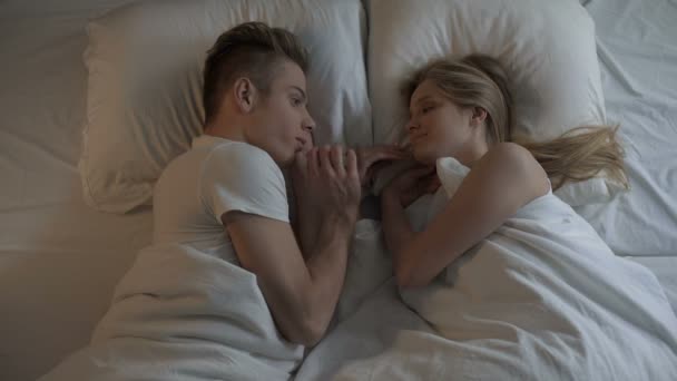 Couple in love holding hands lying in bed at night time, romantic moments — Stock Video