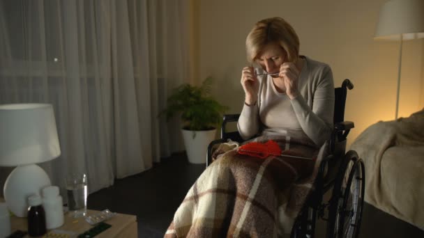 Old tired woman in wheelchair wearing glasses trying to knit, poor eyesight — Stock Video