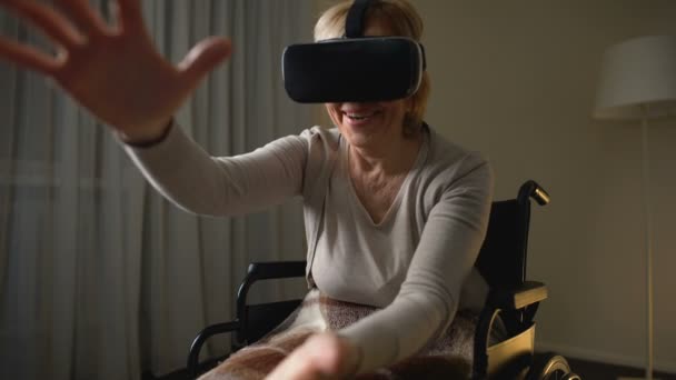 Возбужденная старшая леди в инвалидной коляске развлекается в современной виртуальной реальности — стоковое видео