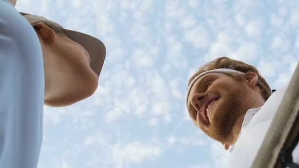 Zwei Sportpartner sprechen nach gutem Spiel auf Tennisplatz in der Nähe des Netzes, Ansicht von unten — Stockvideo