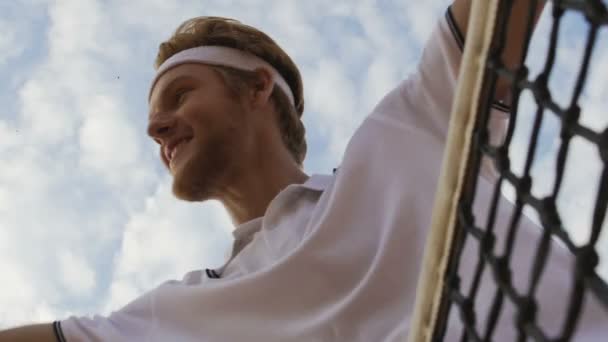 Junger Mann zeigt Siegergeste, bleibt in der Nähe des Tennisnetzes, gutes Spiel, Blick nach unten — Stockvideo