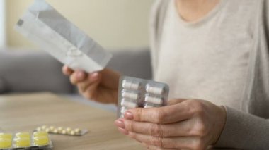 Üst düzey kadın hapları masada, zararlı kendi kendine ilaç talimatı okuma