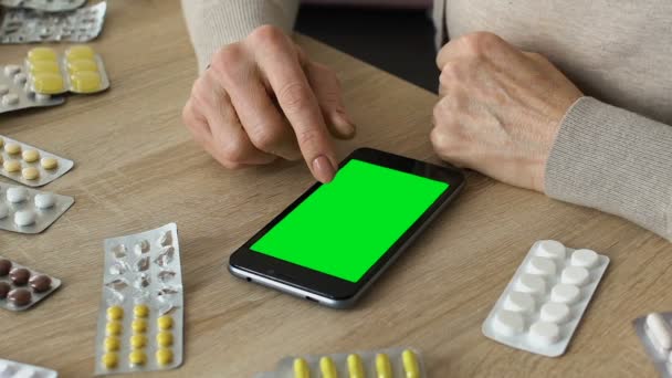 Grandmother scrolling smartphone app, ordering medicine online, green screen — Stock Video