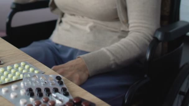 Одинокая женщина в инвалидном кресле в окружении медицины, опасное самолечение — стоковое видео