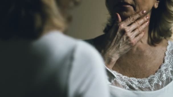 Senior kvinna som tittar på sin spegelbild, upprörd med åldrande och slapp hud — Stockvideo