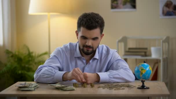 Masculino contando dinheiro e vendo pequeno globo, planejando viagem de férias, turismo — Vídeo de Stock