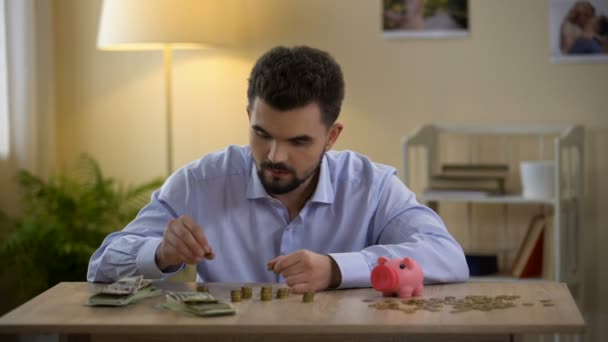 Uomo che conta soldi e mette monete in salvadanaio, alfabetizzazione finanziaria, bilancio — Video Stock