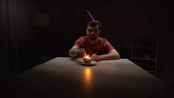 Homem solitário acendendo vela no cupcake de aniversário, sentado sozinho no quarto escuro — Vídeo de Stock