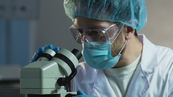 Αρσενικό επιστήμονας που εργάζεται με μικροσκόπιο σε εργαστήριο φαρμακοβιομηχανίας — Αρχείο Βίντεο